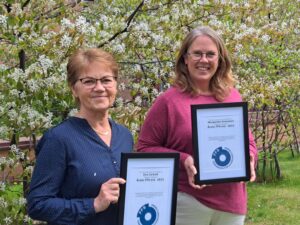 Eva Carholt och Margareta Svensson håller glatt upp sina utmärkelser (en tavla med FFS logga och motivering till utnämningen) 